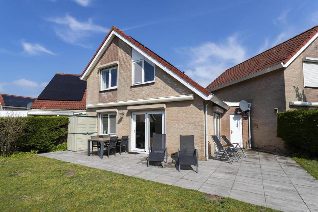 a patio with chairs and a table in front of a house at Mosselbank 073 - Noordzeepark Ouddorp in Ouddorp