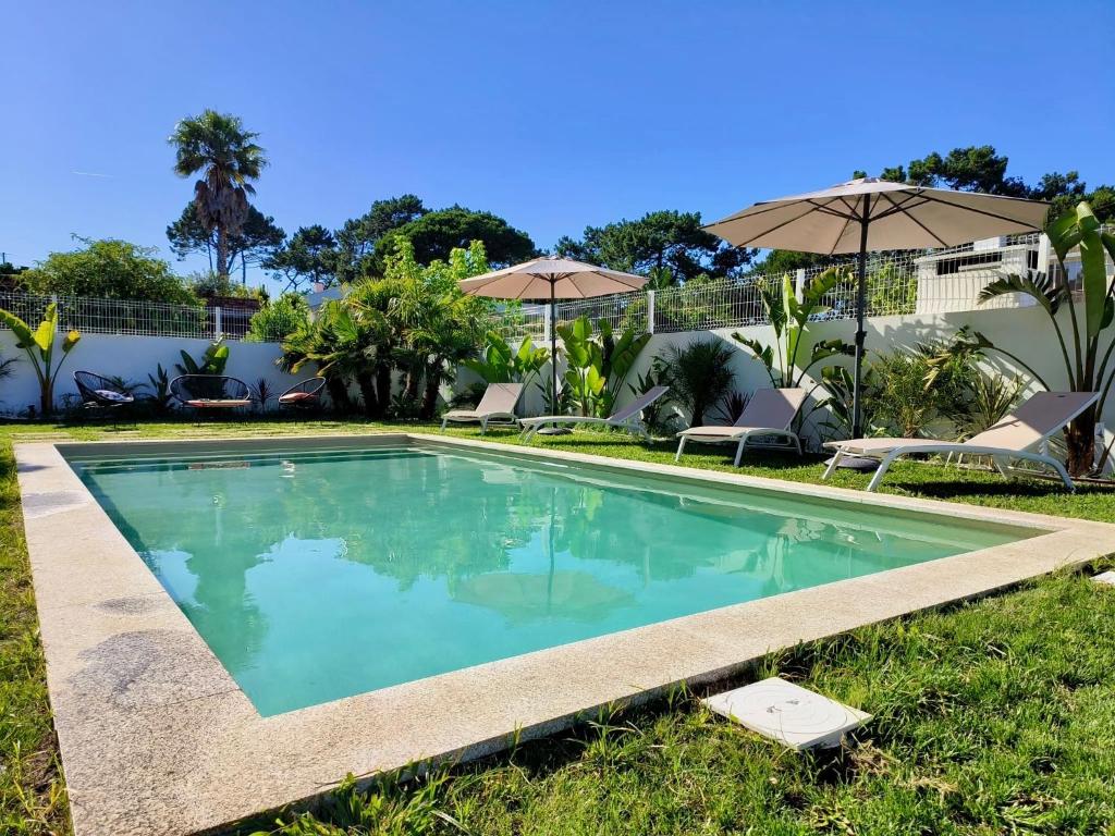 a swimming pool in the yard with umbrellas at Sunset Cabedelo Residence - Heated Pool in Viana do Castelo