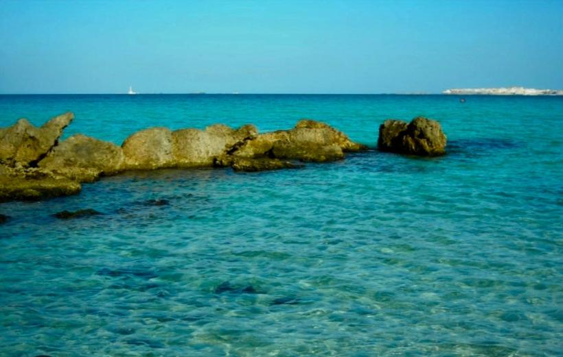 a group of rocks in the ocean with blue water at Casa Cerasoli Gallipoli in Gallipoli