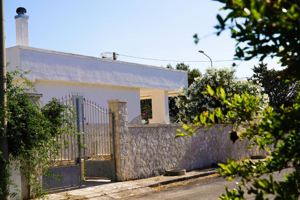 a white house with a gate and a fence at Casetta Dolce Mare - FELICITA' a DUE PASSI dal MARE in Villanova di Ostuni