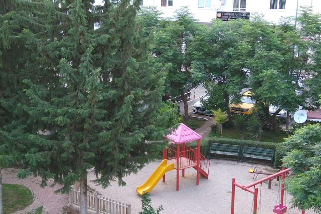 een speeltuin met een glijbaan in een park met bomen bij MCKızılsaray Apart in Antalya