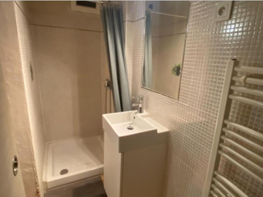 une salle de bain blanche avec un lavabo et une douche dans l'établissement Studio du vieux port de la ciotat, à La Ciotat