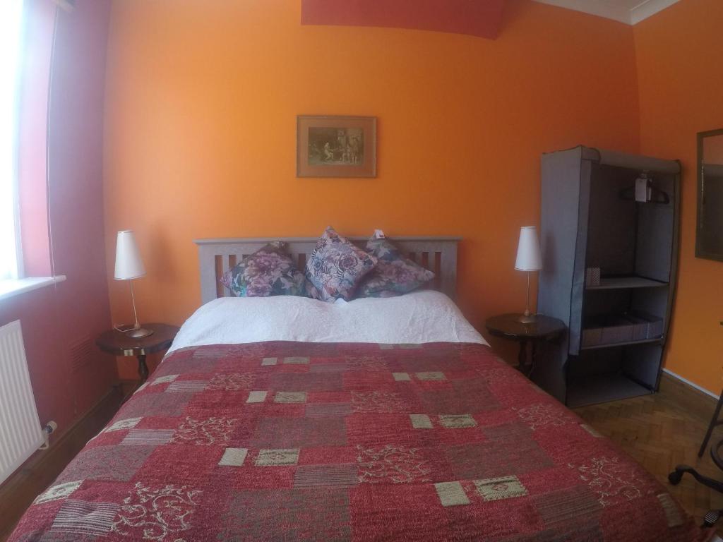 a bedroom with a bed with an orange wall at Carlton Mansions - The Red Room in Bristol