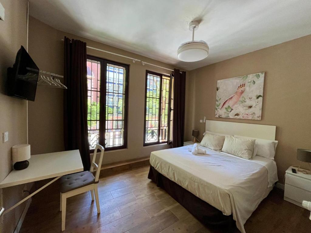 Un dormitorio con una cama y un escritorio y ventanas. en Palacete de la Almudayna, en Madrid