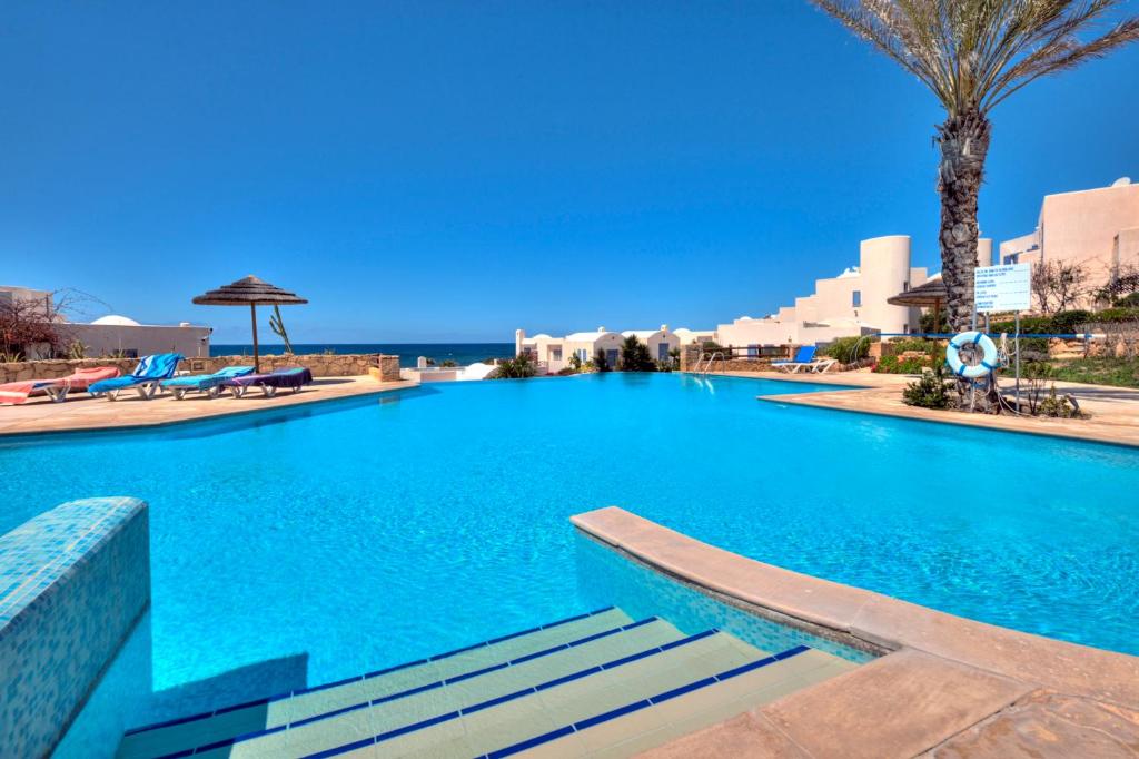 - une piscine d'eau bleue avec des palmiers dans l'établissement Apollo Beach Villa 63, à Paphos