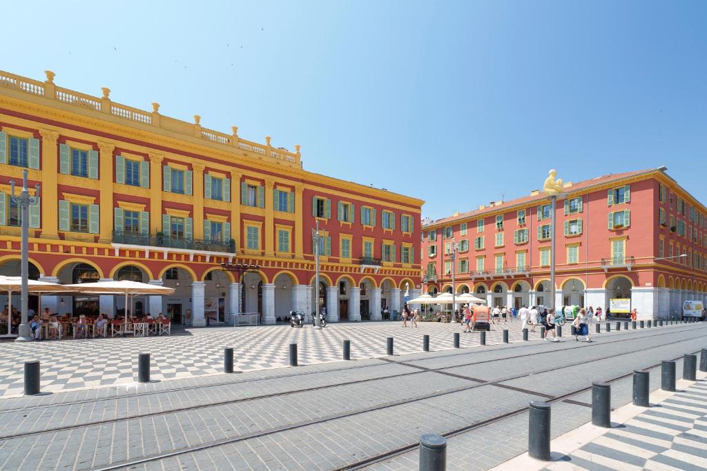 un groupe de bâtiments avec des gens qui marchent devant eux dans l'établissement Nice Renting - 3 MASSENA - Chic Escape Luxury Duplex Place Massena, à Nice