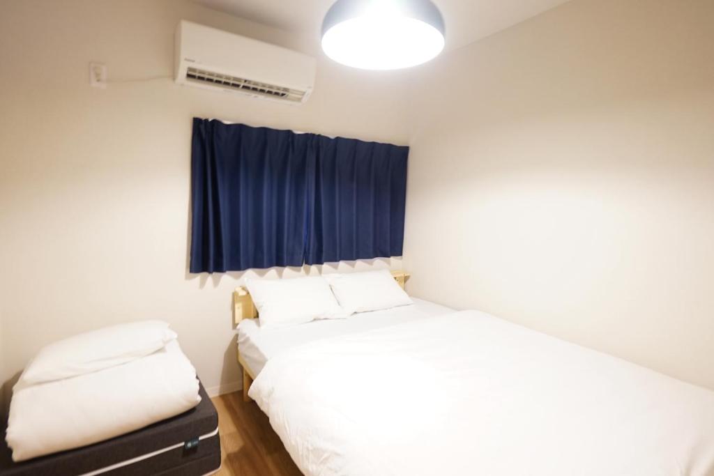 a bedroom with two beds and a blue curtain at 【SHO-HOUSE】駅から徒歩3分 in Osaka