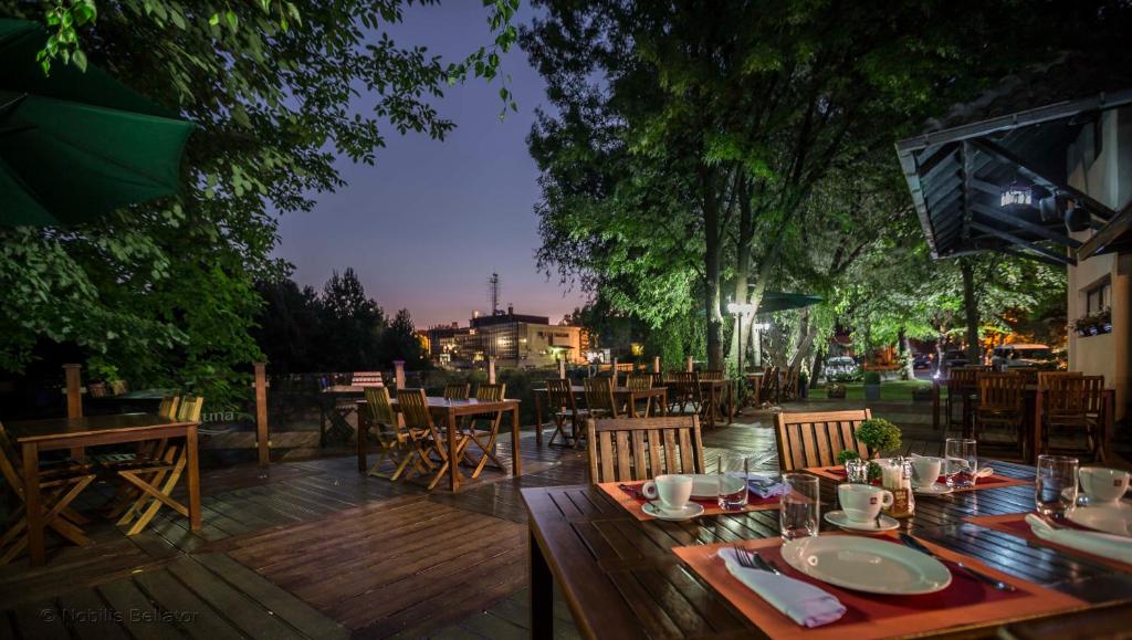 un patio con mesas y sillas de madera en Garni Hotel Plava Laguna, en Ćuprija