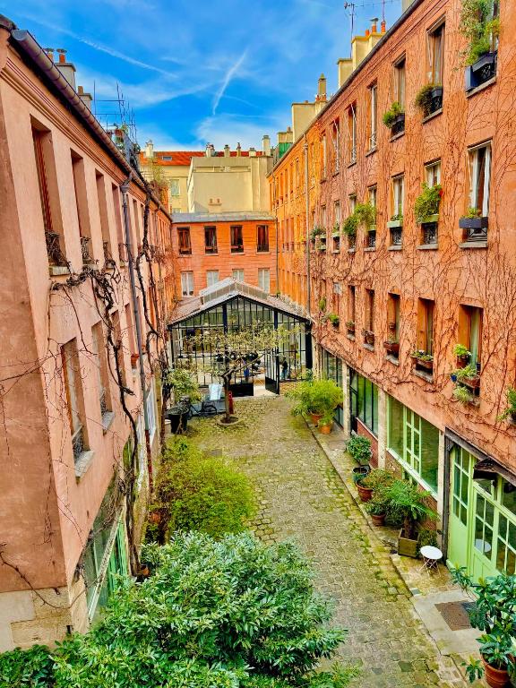 une allée entre deux bâtiments avec une serre au milieu dans l'établissement Appartement Loft et studio, à Paris