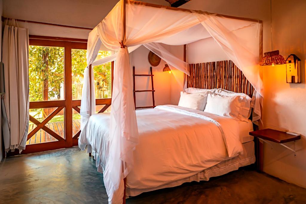 a bedroom with a bed with a canopy at Paka Bangalos, Pousada de Charme em Sergipe in Pacatuba