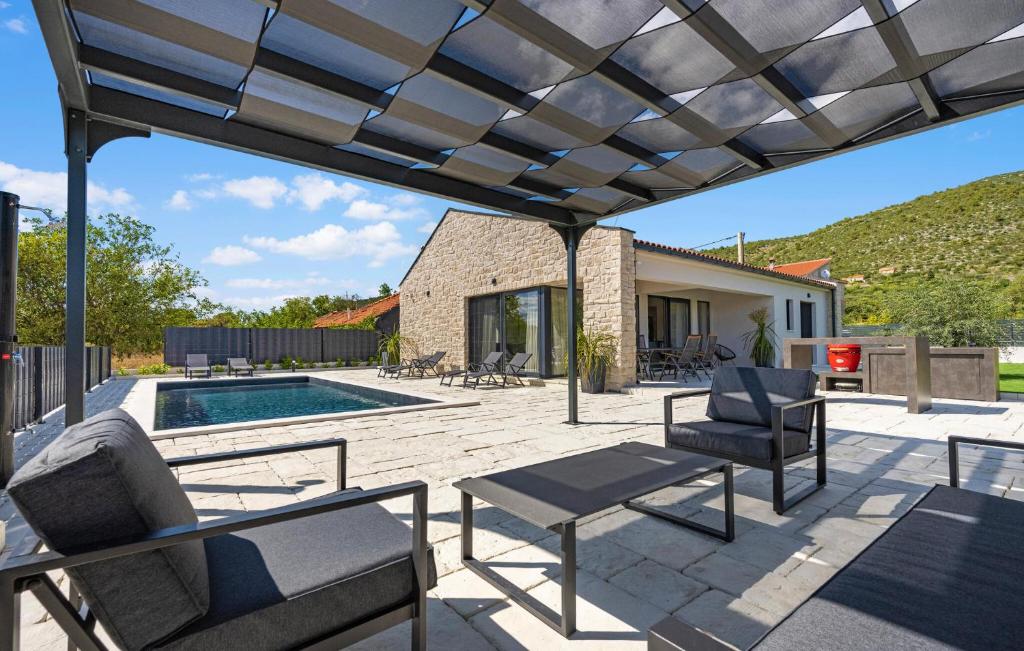Un patio con sillas y una mesa y una piscina. en Stunning Home In Sibenik With Kitchen, en Šibenik