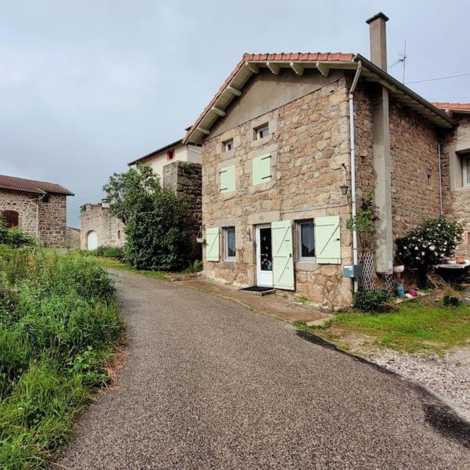 une ancienne maison en pierre avec une route devant elle dans l'établissement Maison de campagne, à Usson-en-Forez