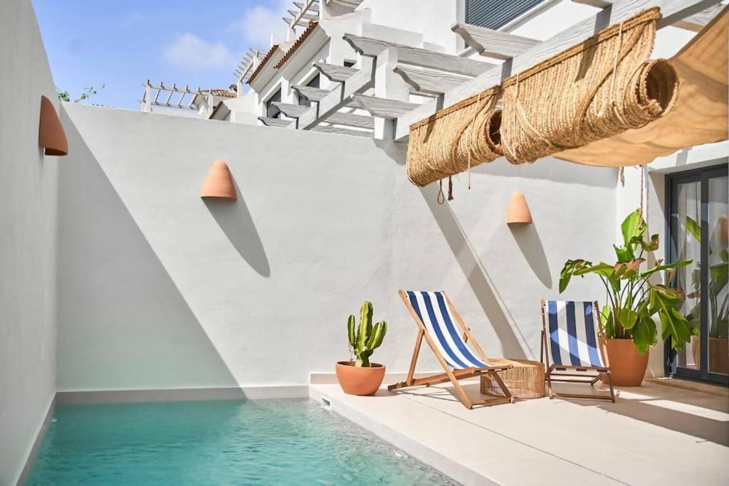 a patio with two chairs and a swimming pool at Esencia Marbella Villas Private Pool in Estepona
