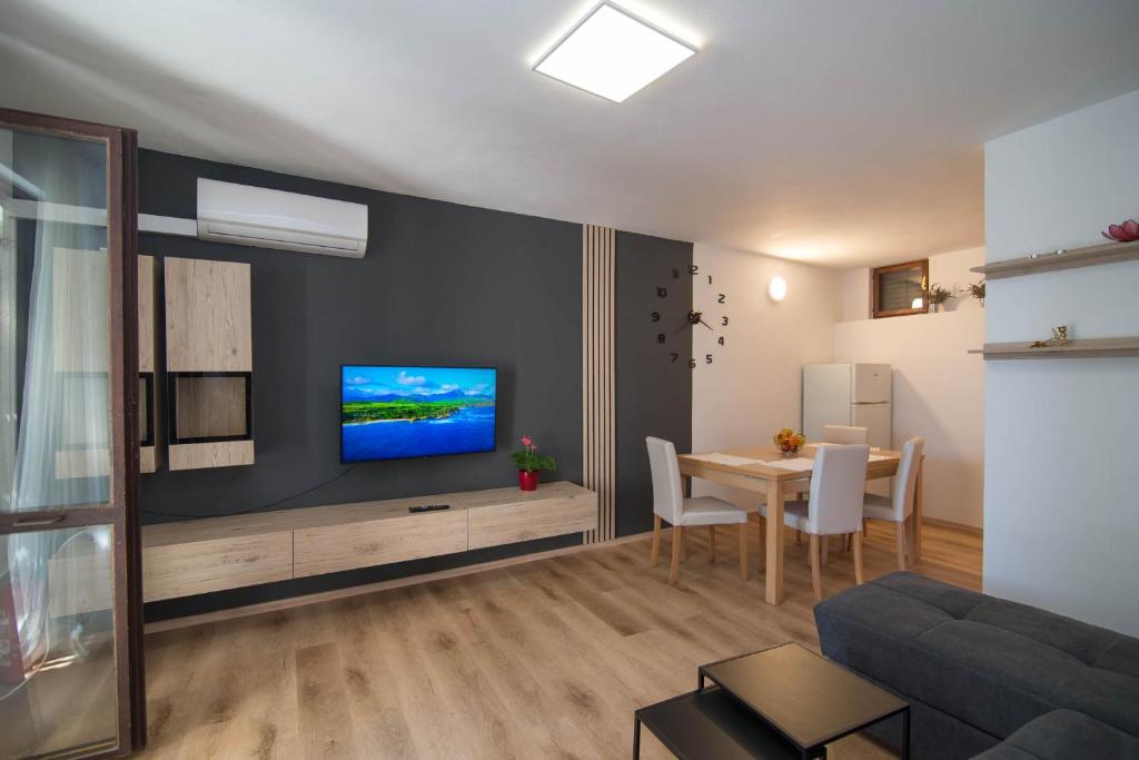 a living room with a table and a tv on a wall at Castello in Mali Lošinj