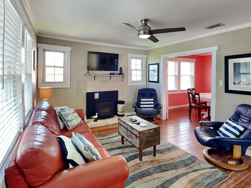 een woonkamer met een leren bank en een open haard bij CB Sunshine Cottage in Carolina Beach