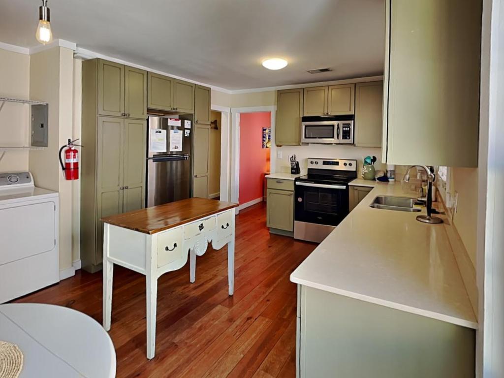 a kitchen with white cabinets and a wooden floor at CB Sunshine Cottage in Carolina Beach