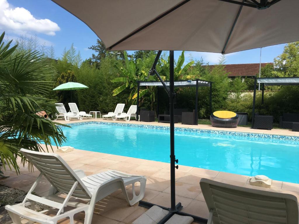 - une piscine avec 2 chaises longues et un parasol dans l'établissement Résidence du parc, à Souillac