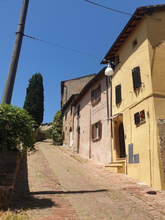 una calle adoquinada junto a un edificio antiguo en Sebastiano, en Colle Val D'Elsa