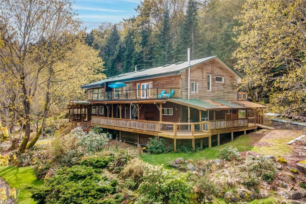 a large wooden house in the middle of a forest at Hummingbird B&B in Gabriola
