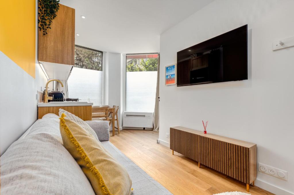 een woonkamer met een bank en een flatscreen-tv bij Lavie Maison Hot Tub Seaside Studio in Nice
