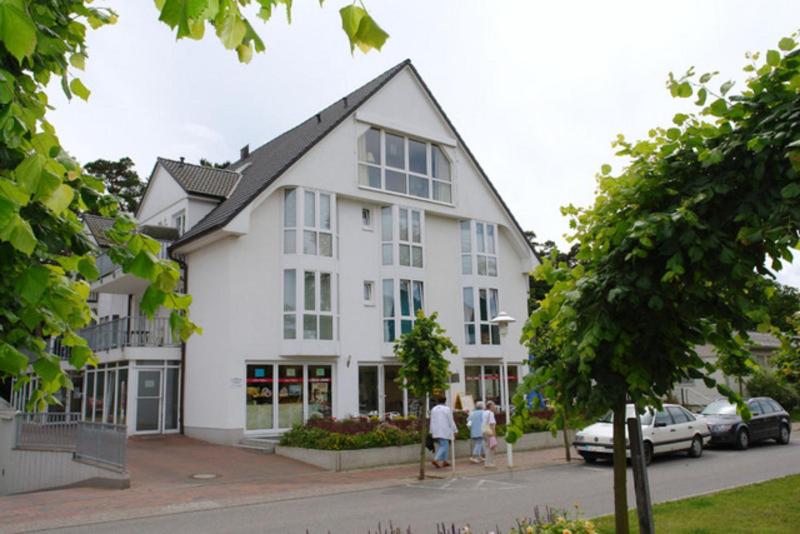 a white building with people walking in front of it at Strandstraße by Rujana in Baabe