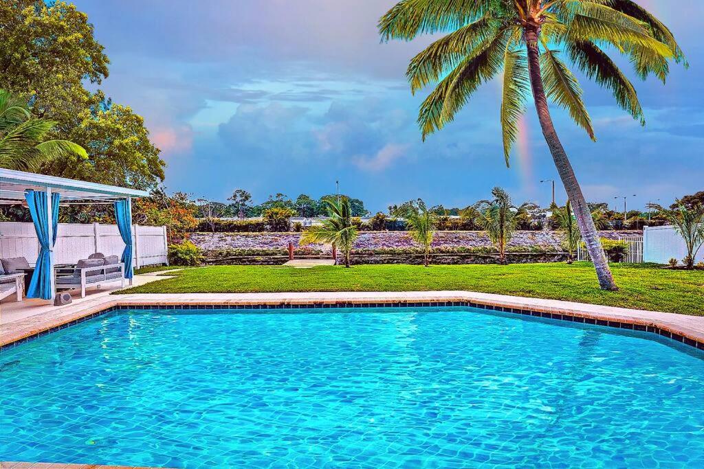 una piscina en un patio con una palmera en NEW Waterfront Tropic Oasis - Heated Pool, Canal, Dock, Air Hockey, en Boynton Beach