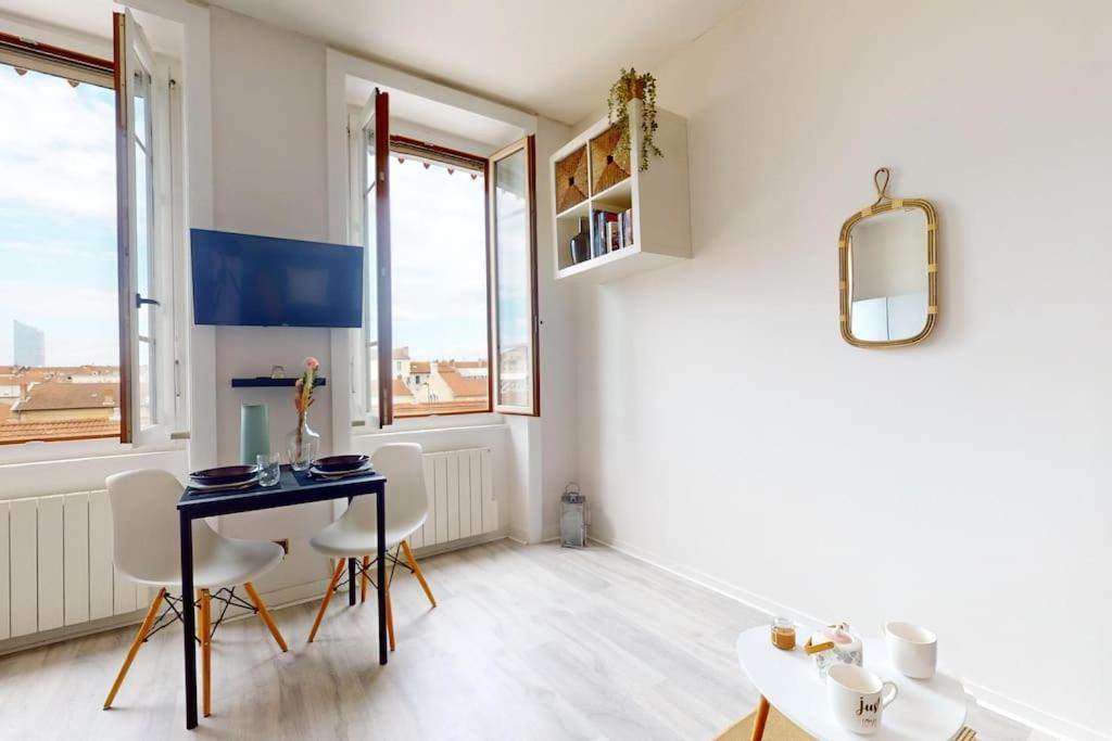 ein Esszimmer mit Tisch und Stühlen und Fenstern in der Unterkunft Le Cocon dans les Nuages in Villeurbanne