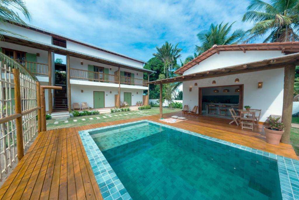 a villa with a swimming pool and a house at Jardim Cumuru - Suítes in Cumuruxatiba