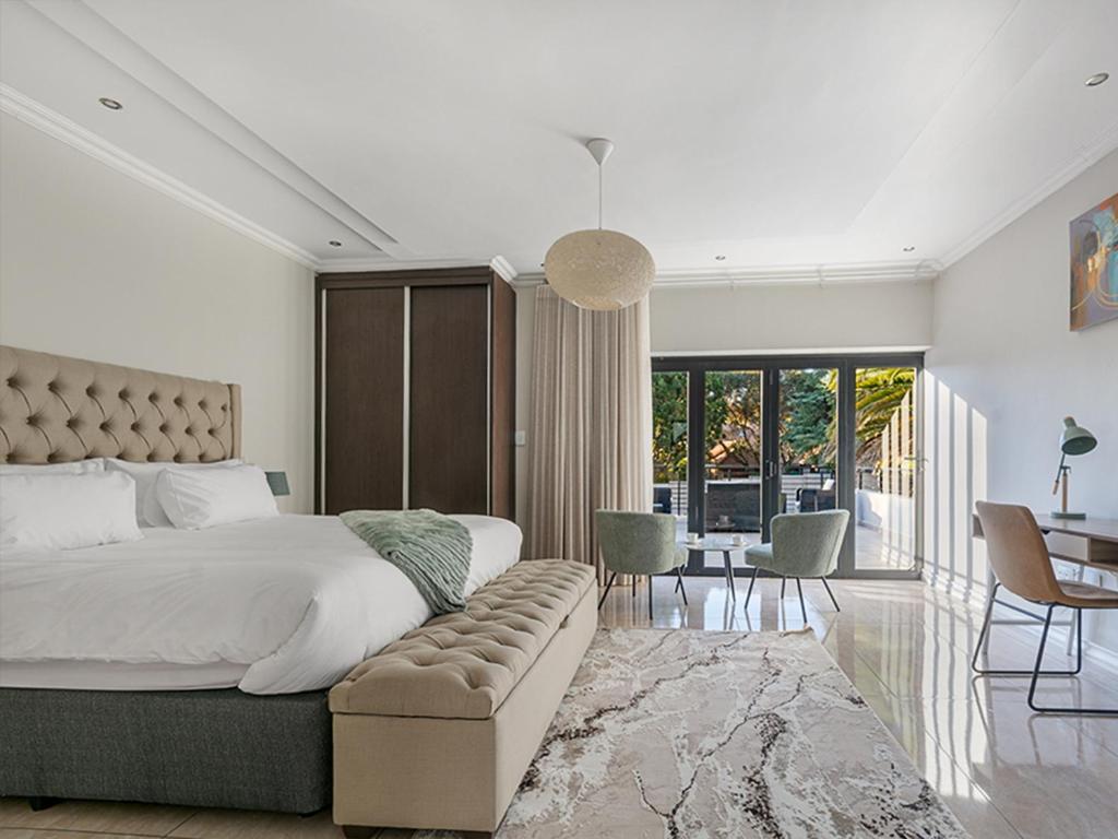 a bedroom with a large bed and a table and chairs at Self Checkin - Luxury Tranquil Apartment in Guesthouse in Johannesburg