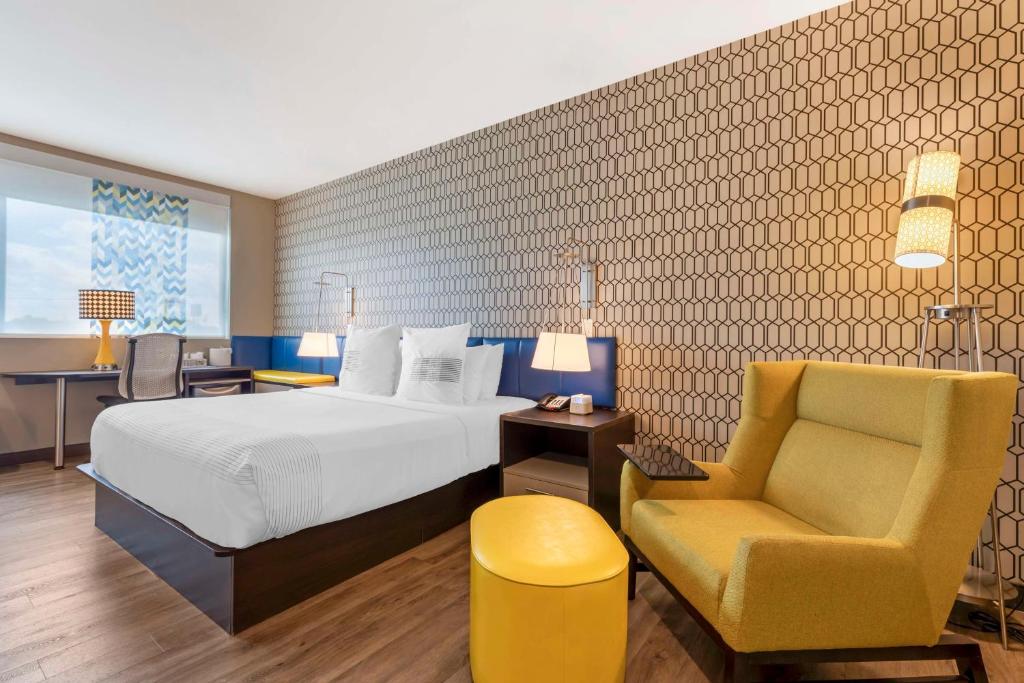 a hotel room with a bed and a chair at GLō Best Western Dallas South DeSoto in DeSoto