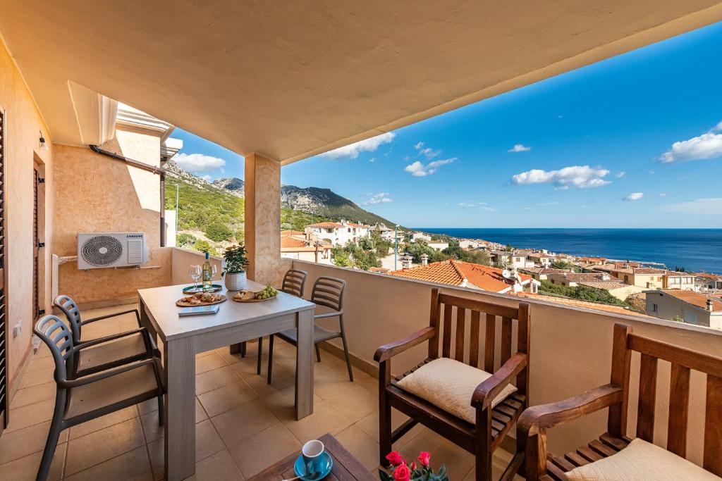 a balcony with a table and chairs and a view of the ocean at Casa Marco Sardinia Domus in Cala Gonone