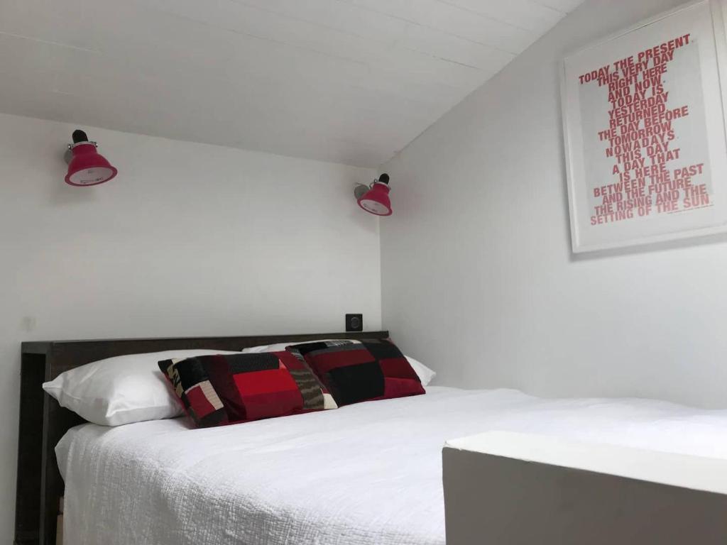 un letto bianco con un cuscino rosso e nero sopra di Le Rooftop Collioure a Collioure