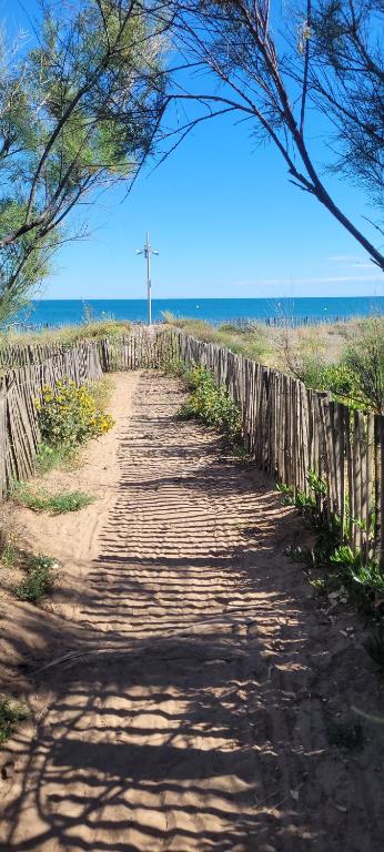 un chemin de terre à côté d'une clôture et de l'océan dans l'établissement Appartement bord de mer, à Portiragnes