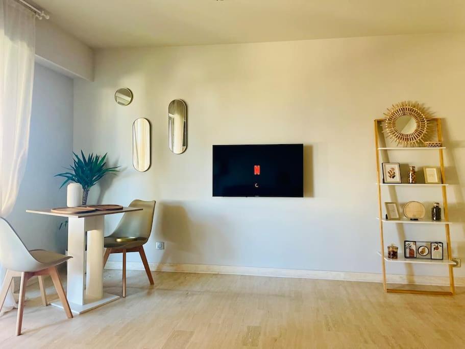 un salon avec une table et une télévision au mur dans l'établissement 17Bijou-Plage, à Antibes