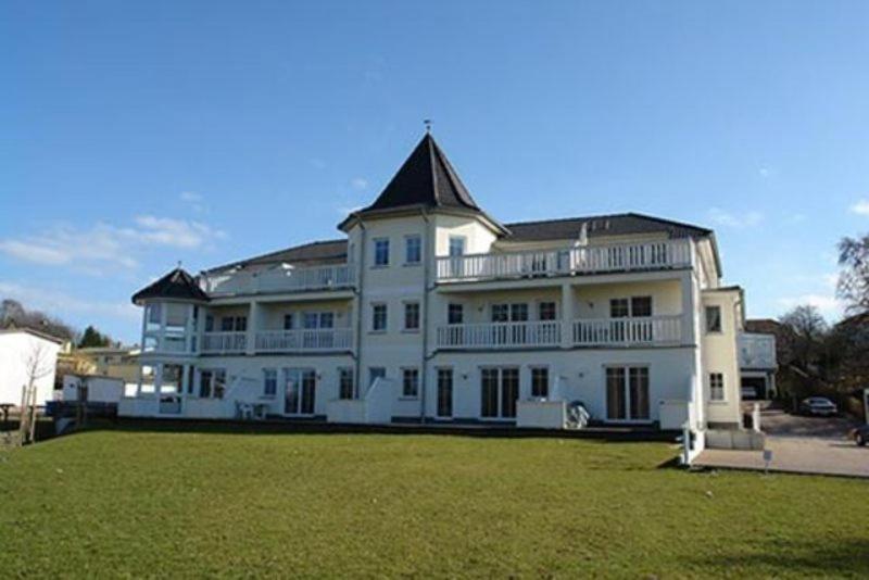 ein großes weißes Haus mit einem großen Rasenplatz in der Unterkunft Schlösschen am Schmachter See by Rujana in Binz