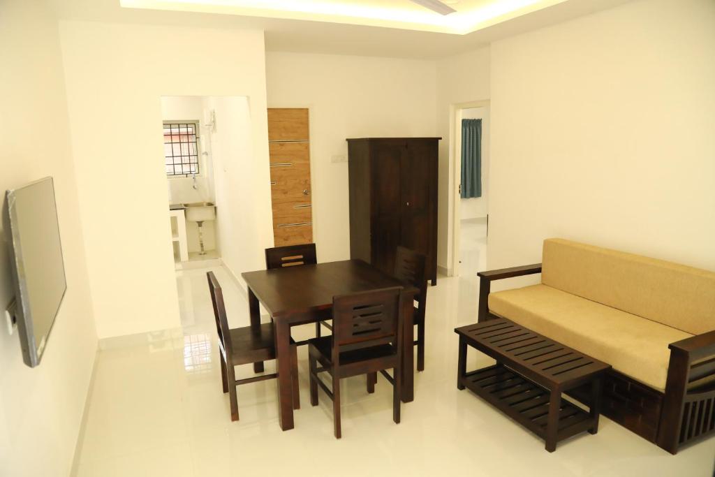 a dining room with a table and chairs and a couch at F-1 Tulsi By The Peace in Chennai
