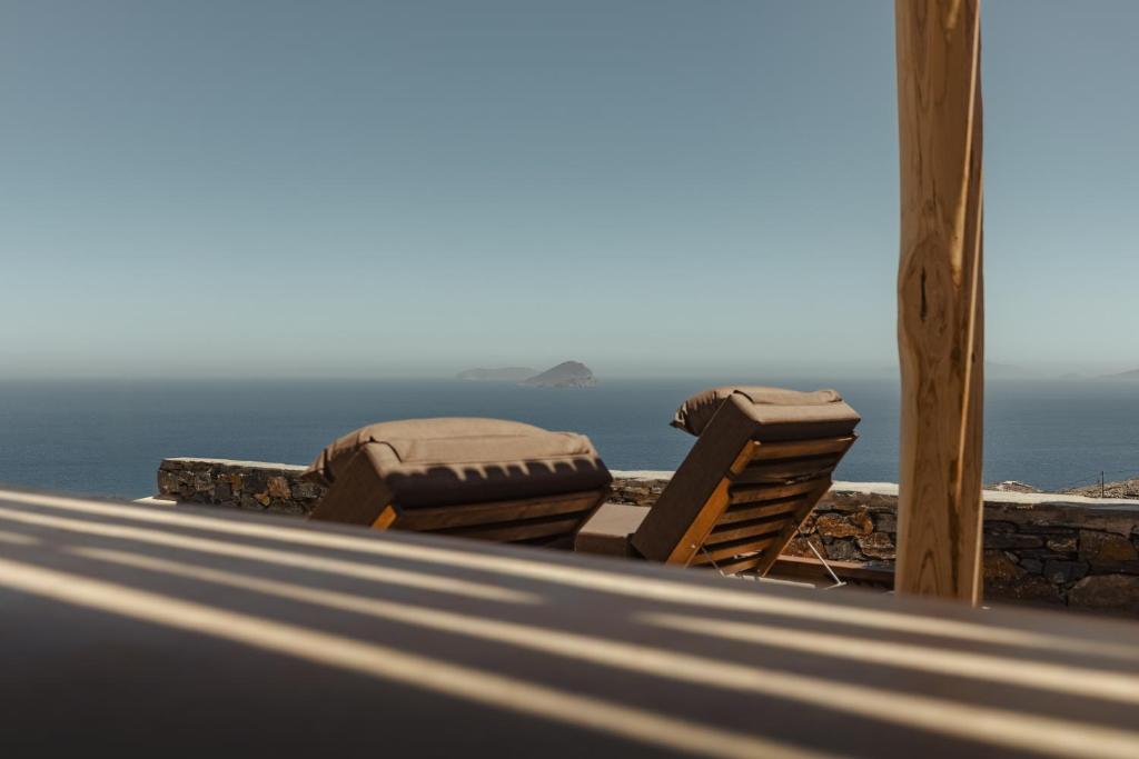 two chairs sitting on a porch overlooking the ocean at Piperi Suites in Kithnos
