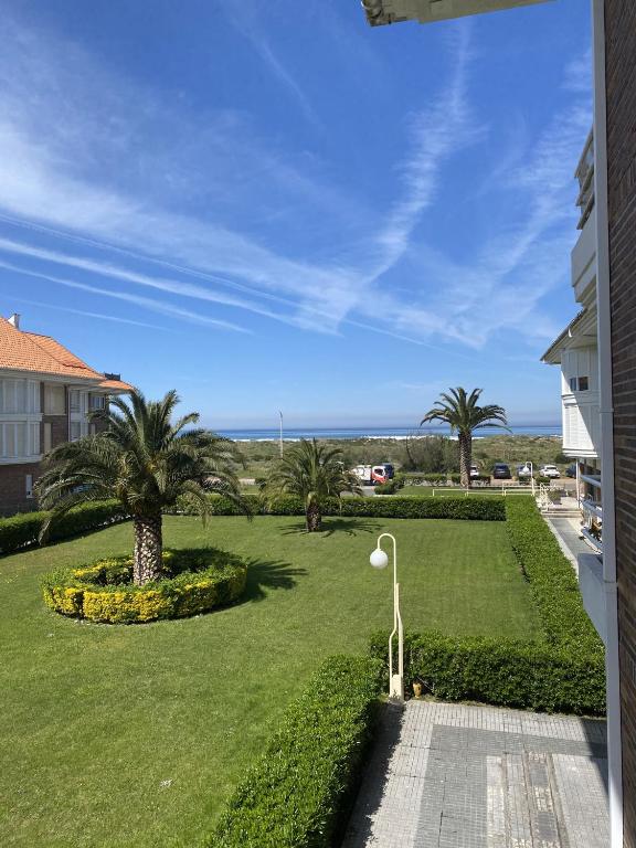 a view of a lawn with palm trees and a street light at Apartamento con vistas al mar playa Berria-Santoña in Santoña