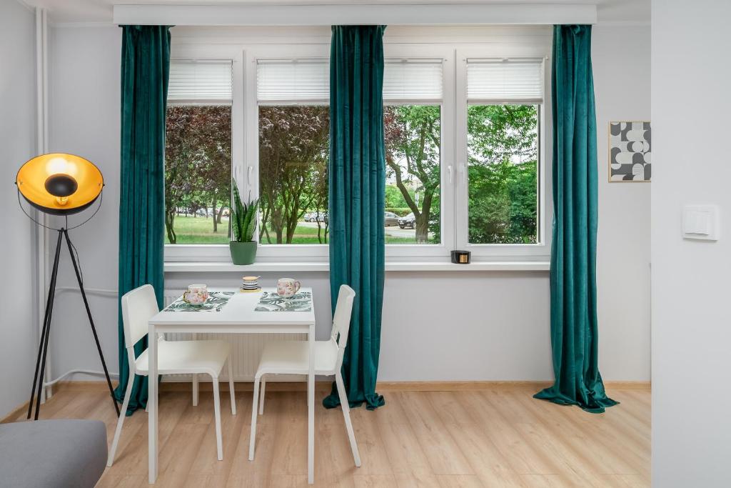 a dining room with green curtains and a table with chairs at Apartament Stella in Częstochowa