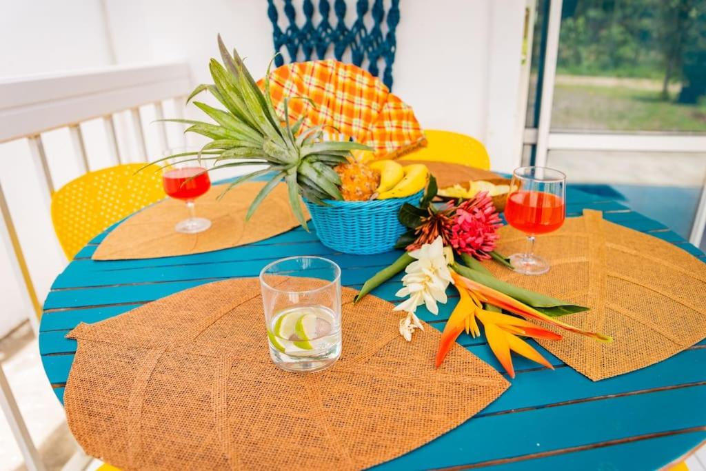 a blue table with a bowl of fruit and drinks at Bungalow Saphir in Le Gosier