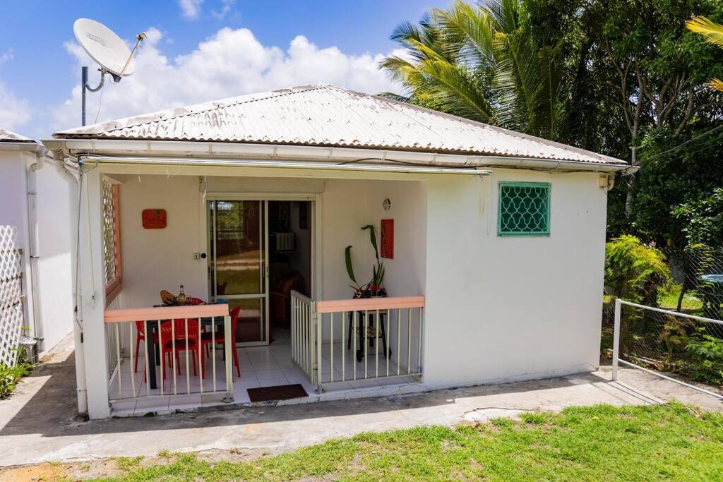 a small white house with a porch and a door at Bungalow Rubis in Le Gosier