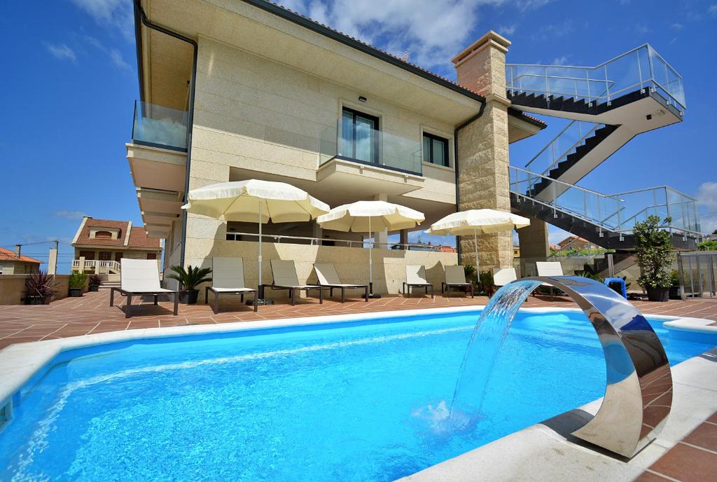a swimming pool in front of a house at GALIHOST - Apartamentos Vento Mareiro in Sanxenxo