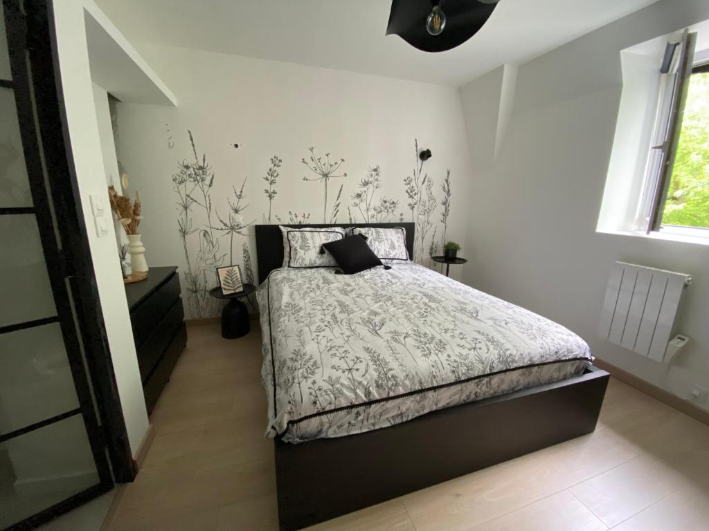 ein Schlafzimmer mit einem Bett mit einer schwarz-weißen Bettdecke in der Unterkunft L'atelier d'Arches in Charleville-Mézières
