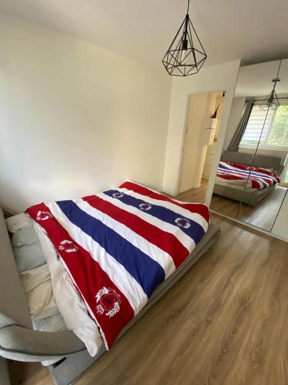 a bed with a red white and blue blanket in a room at Appartement proche La Villette avec 2 balcons in Pantin