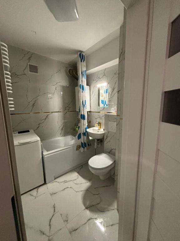 a bathroom with a white toilet and a sink at Apartament Joanna in Kamienna Góra