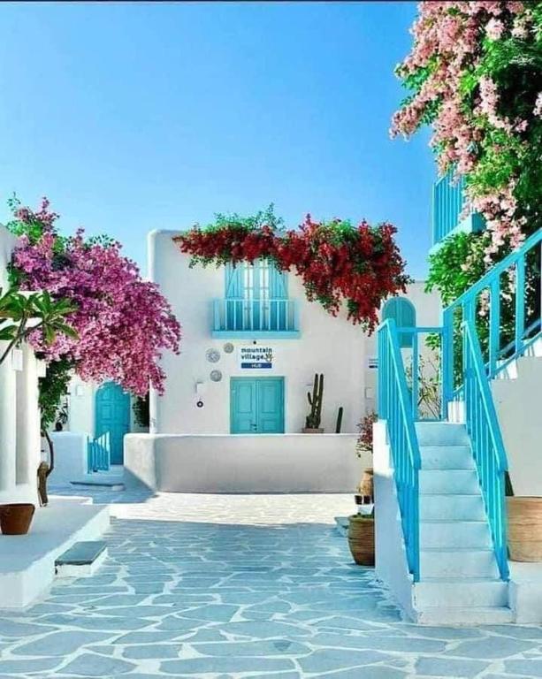 a white building with blue doors and flowers at Villa Mountain View North Coast ماونتن فيو رأس الحكمه in Ras Elhekma