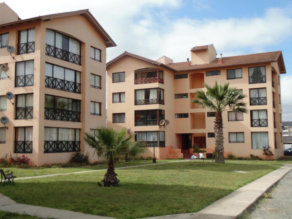 un edificio con palmeras delante en QVEM Propiedades, en La Serena