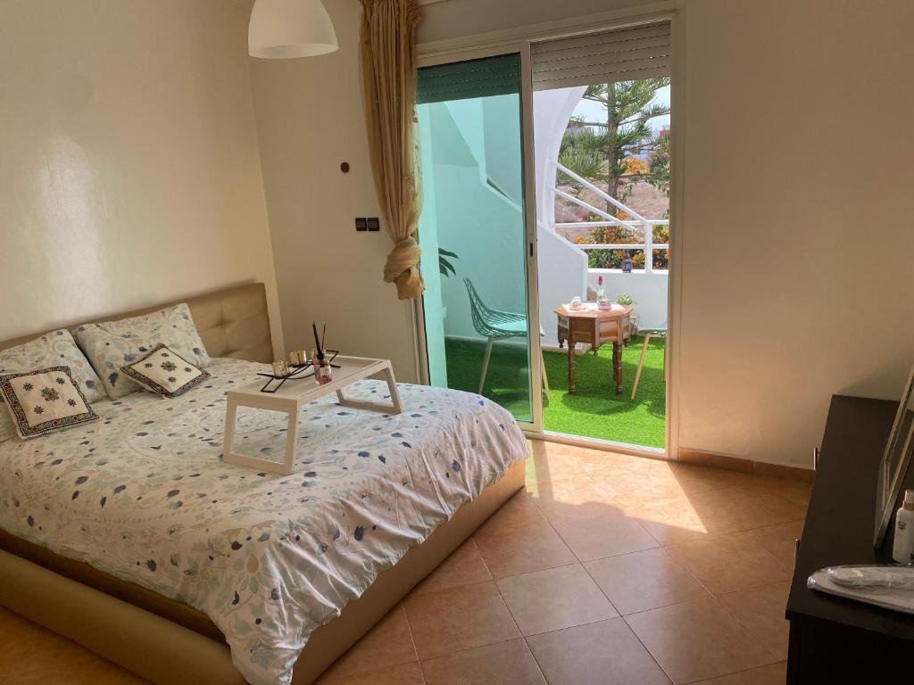 a bedroom with a bed and a balcony with a table at calm and secure residence with pool in Sidi Bouzid