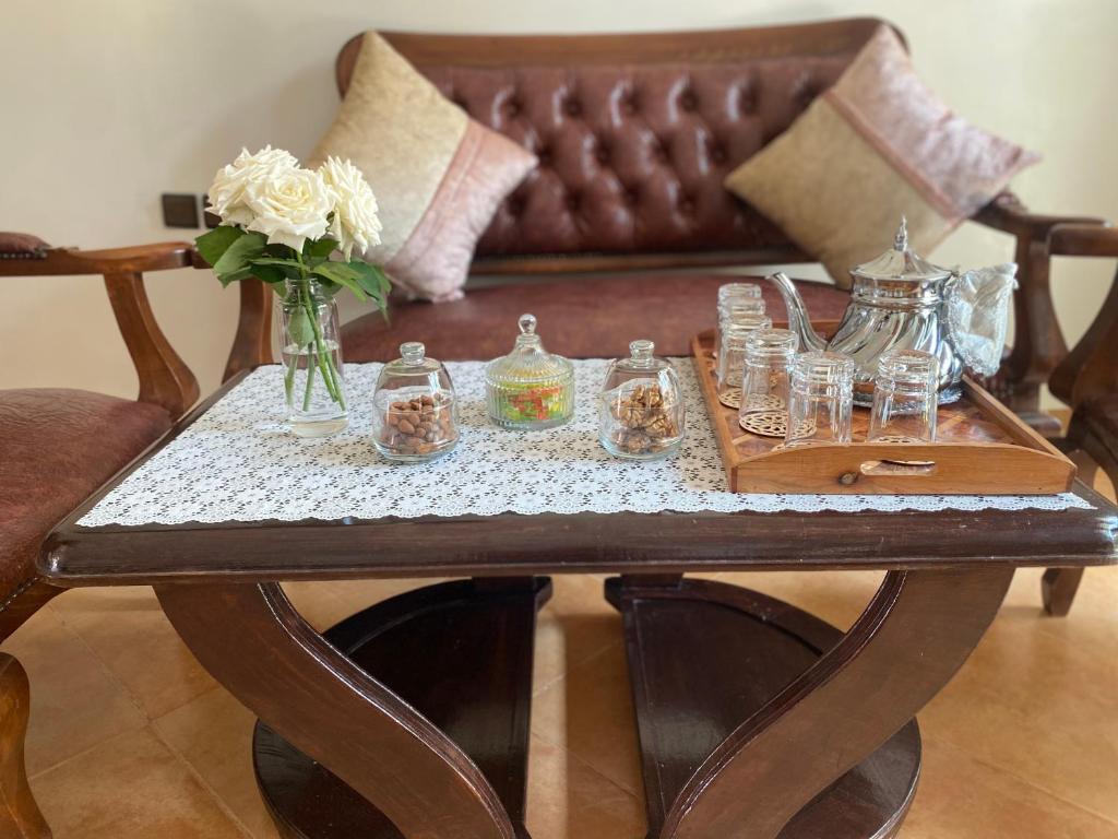 a coffee table with a vase of flowers and glasses on it at calm and secure residence with pool in Sidi Bouzid