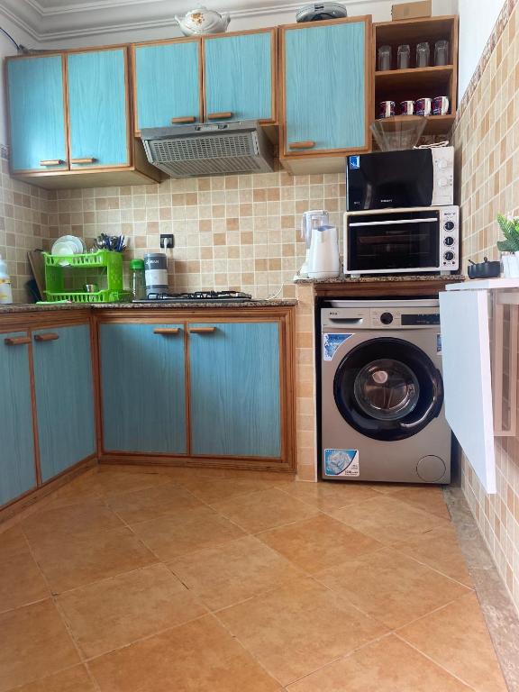a kitchen with a washing machine and a microwave at calm and secure residence with pool in Sidi Bouzid